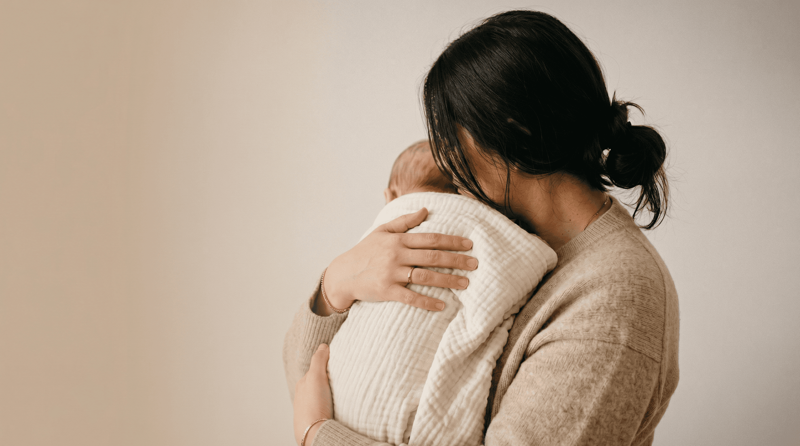 A mother holding her baby close in soft natural light