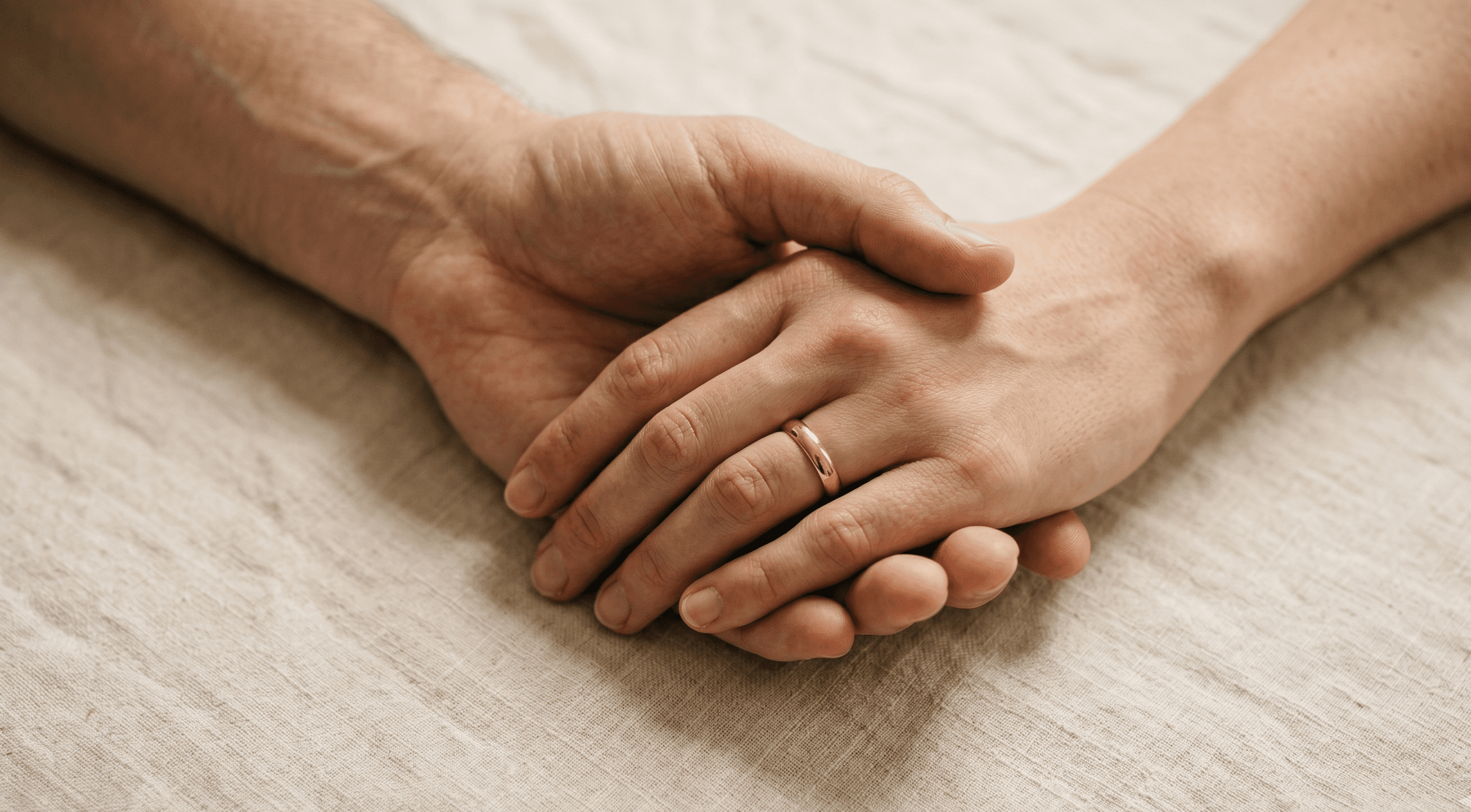 Two hands resting together, one with a wedding ring, representing shared partnership