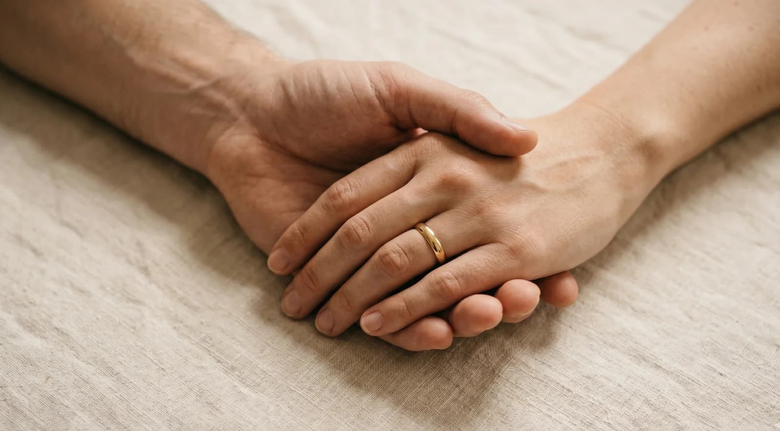 Two hands resting together, one with a wedding ring, representing shared partnership